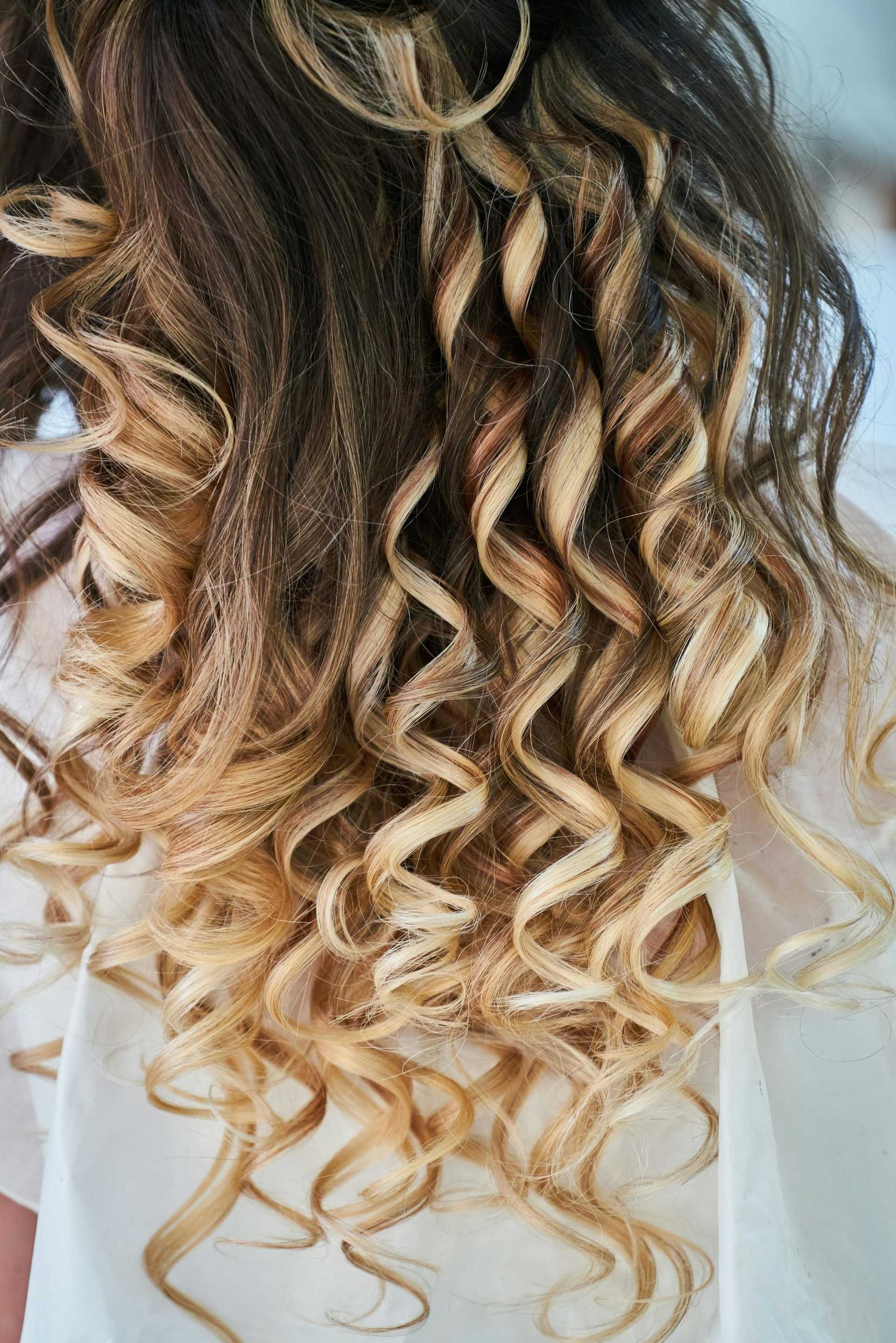 Close-up of woman's hair with blonde highlights and tight, spiral curls.