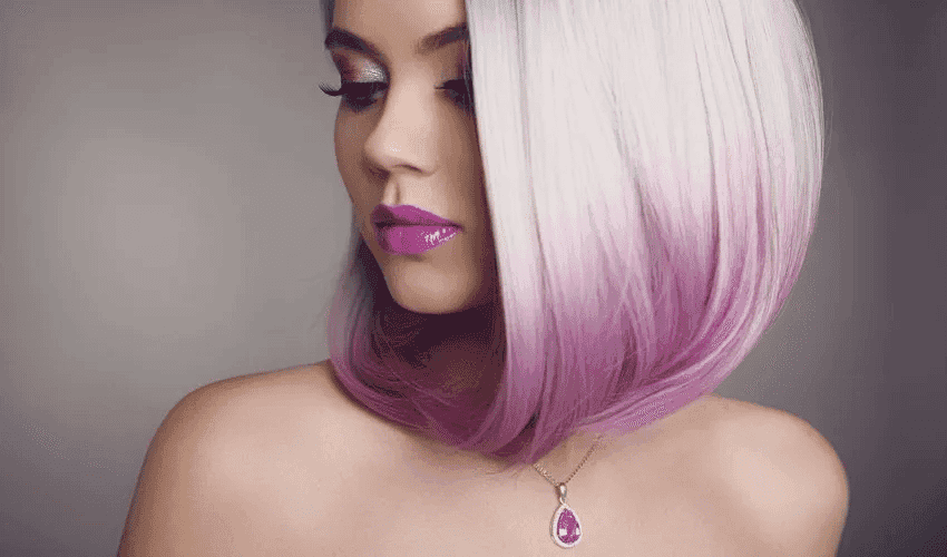 Woman with short, straight hair transitioning from silver to pink, wearing bold lipstick and necklace.