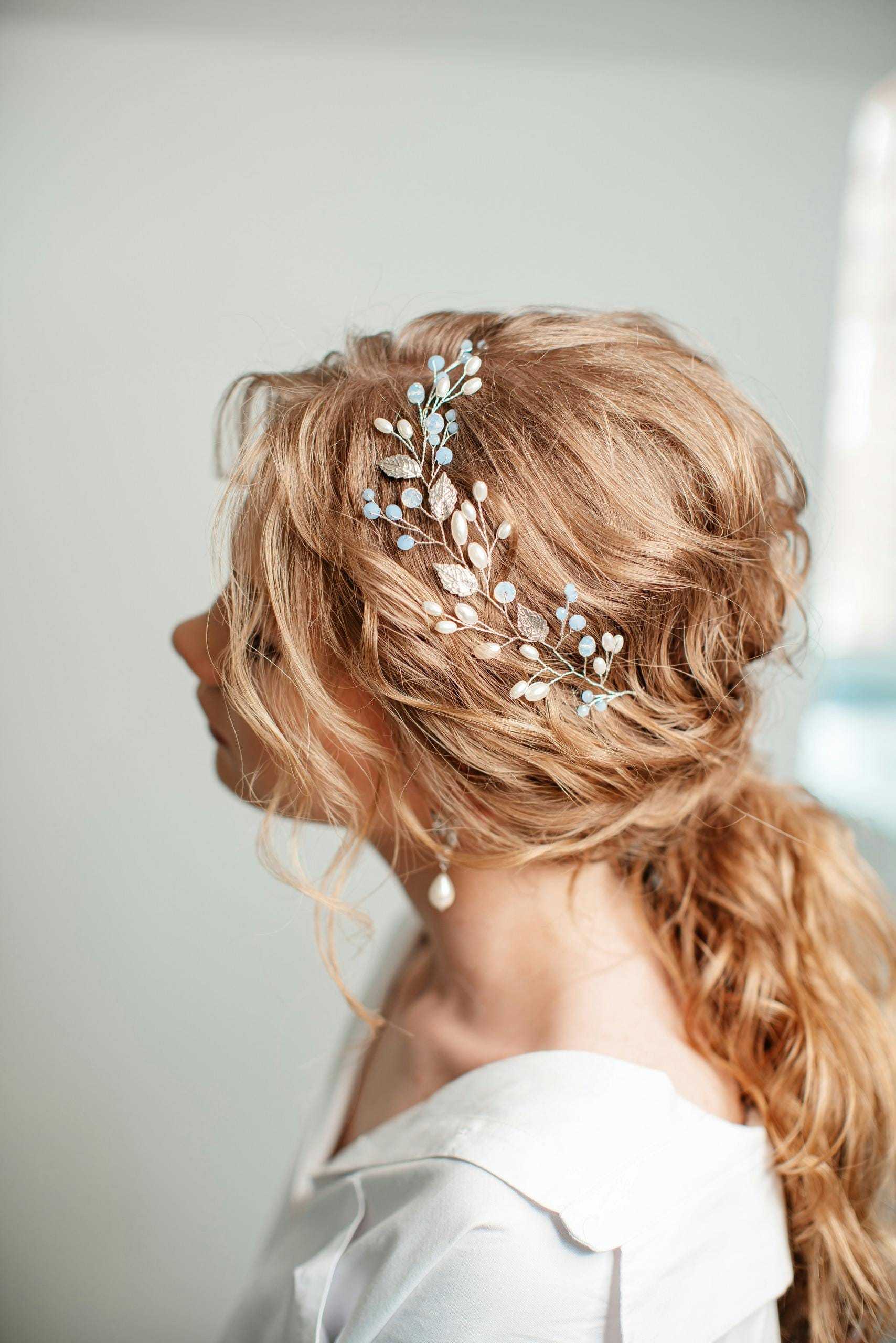 Blonde woman with a braided updo, adorned with a delicate floral hair accessory.